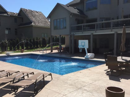 Backyard with an in-ground pool with deck jet fountains on.
