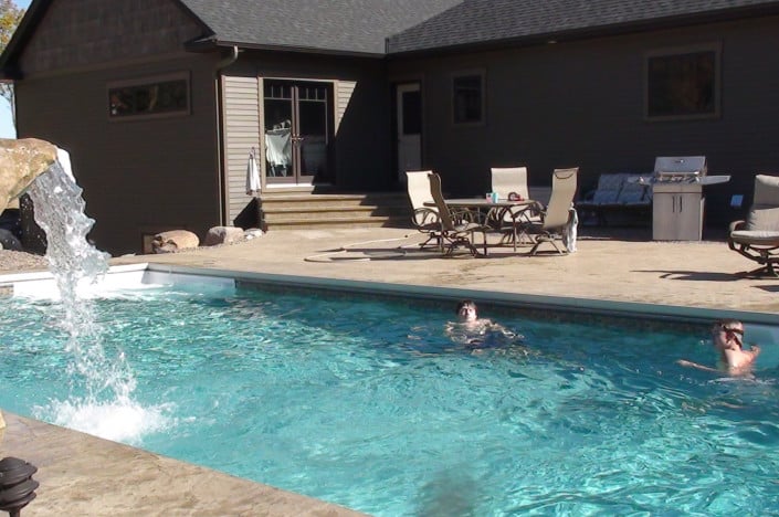 kids swimming in pool with waterfall.