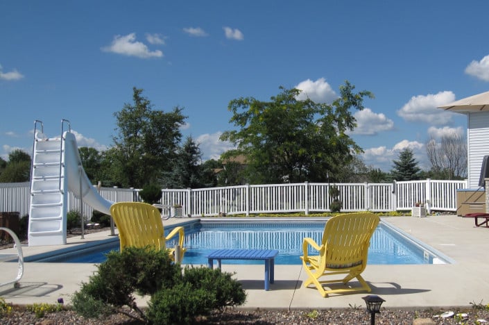 backyard pool with chairs and slide.