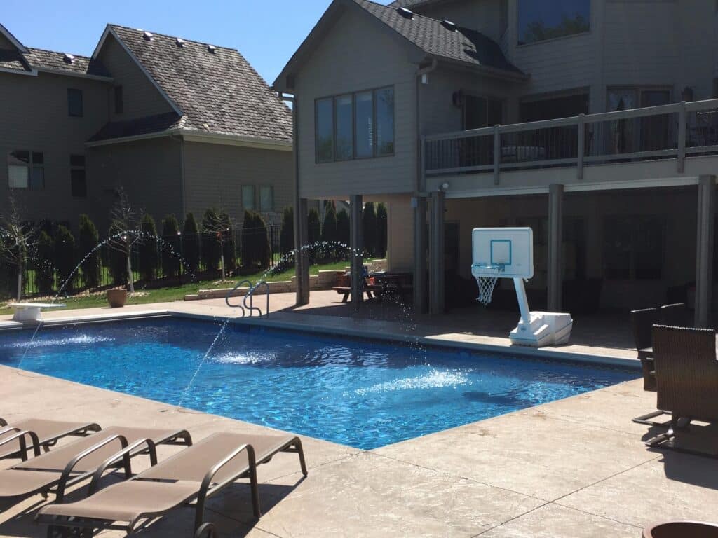 backyard pool with basketball and deck jets.