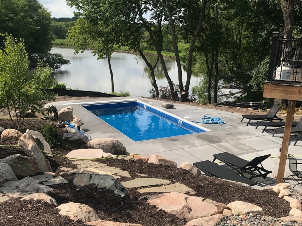 backyard pool with landscaping and pond.