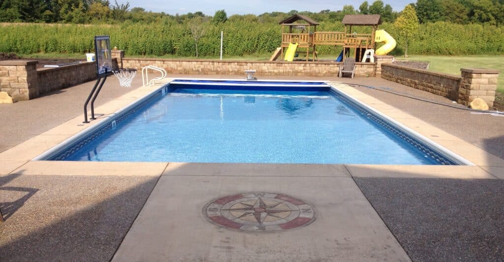 backyard pool with basketball hoop and play set.
